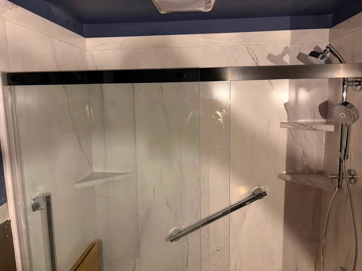 Interior of a completed marble-tiled shower with chrome fixtures, remodeled by C&C Multiservices in Connecticut