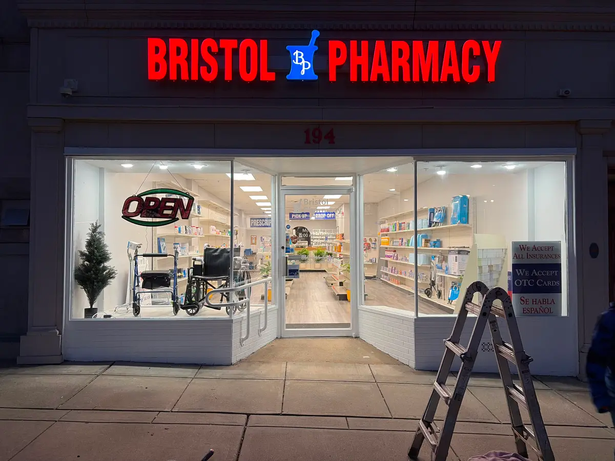 Newly repainted Bristol Pharmacy storefront lit up at night, completed by C&C Multiservices in Connecticut