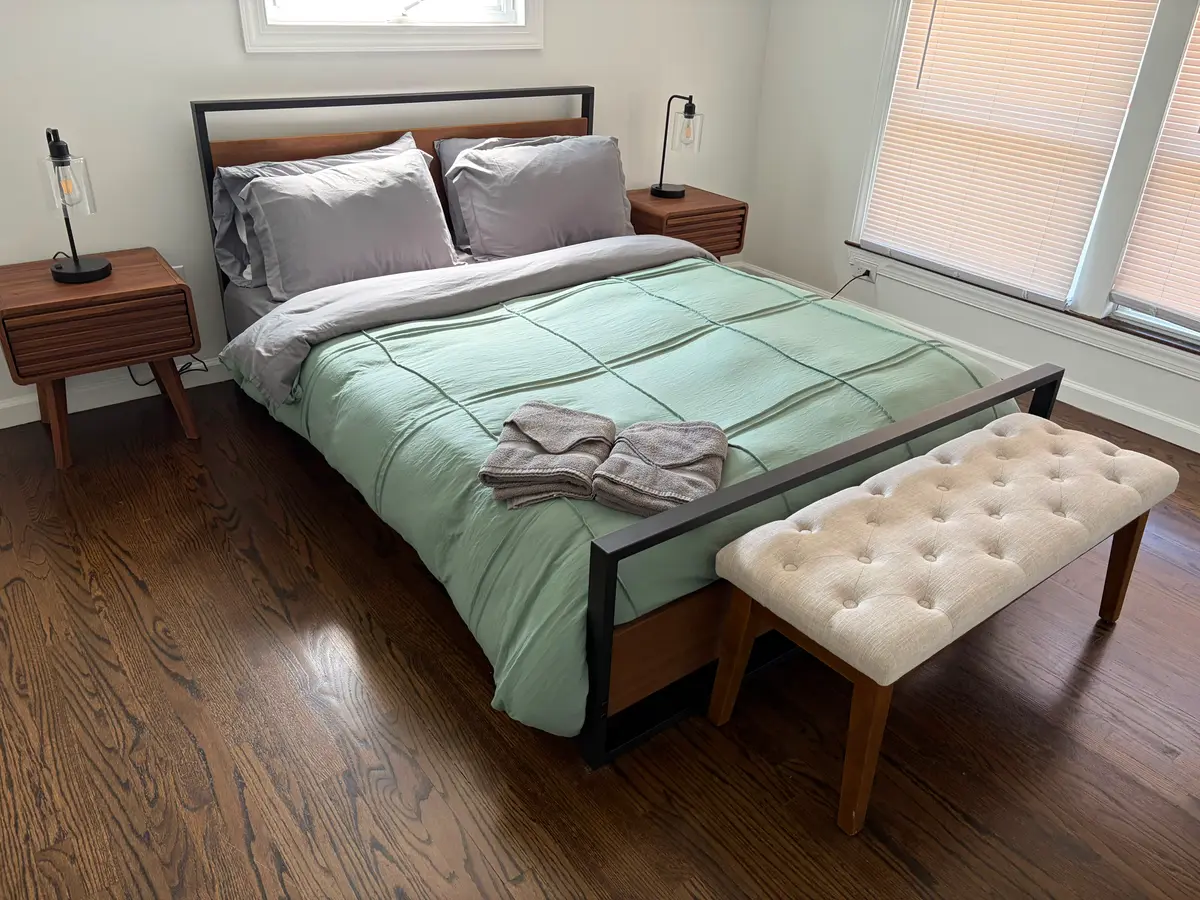 Freshly remodeled bedroom with hardwood floors and green bedding, completed by C&C Multiservices in Connecticut